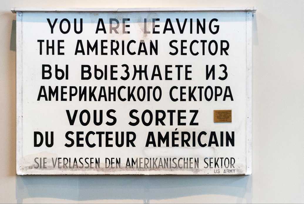 A sign by the US army reading "YOU ARE LEAVING THE AMERICAN SECTOR" along with its translation in Russian, French, and German.
